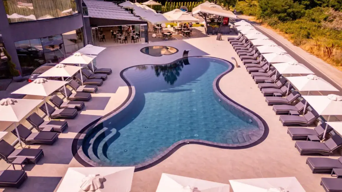 Relaks przy basenie w Laki Hotel & Spa. Leżaki i parasole czekają na gości.