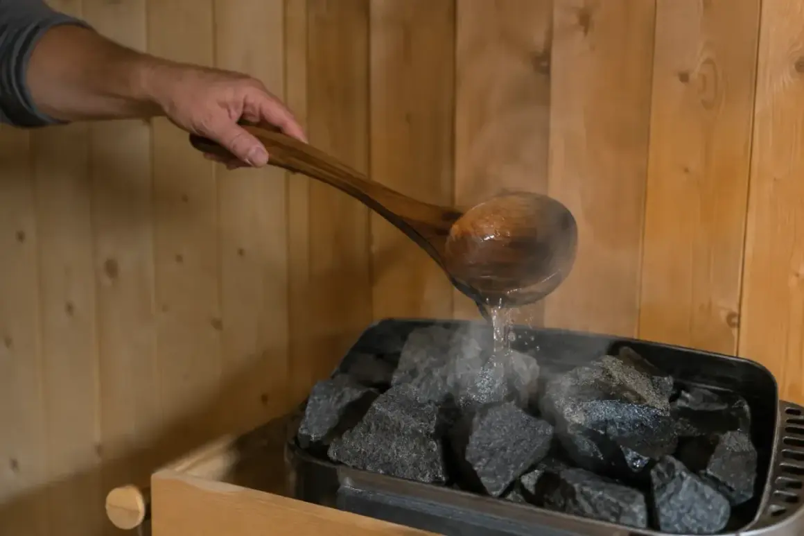 Ein Holzlöffel mit Wasser wird über heiße Steine gegossen, um Dampf zu erzeugen. So kann man sich den Duft von saunahonig selber machen.