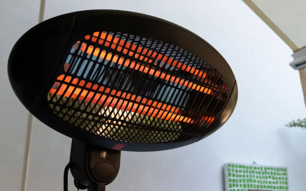 Lampada infrarossi terapia con elementi riscaldanti incandescenti arancioni dietro una griglia nera.
