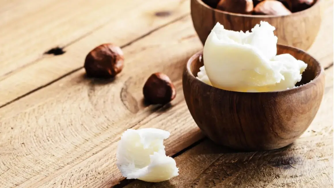Was ist Shea Butter? Cremige, weiße Shea Butter in Holzschalen, dane Nüsse. Natürliche Pflege für die Haut.