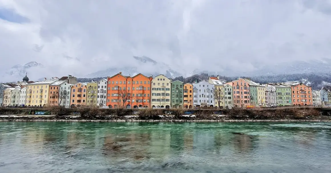 Kolorowe kamienice nad rzeką Inn, w tle ośnieżone góry. Idealne miejsce, by zobaczyć Innsbruck.