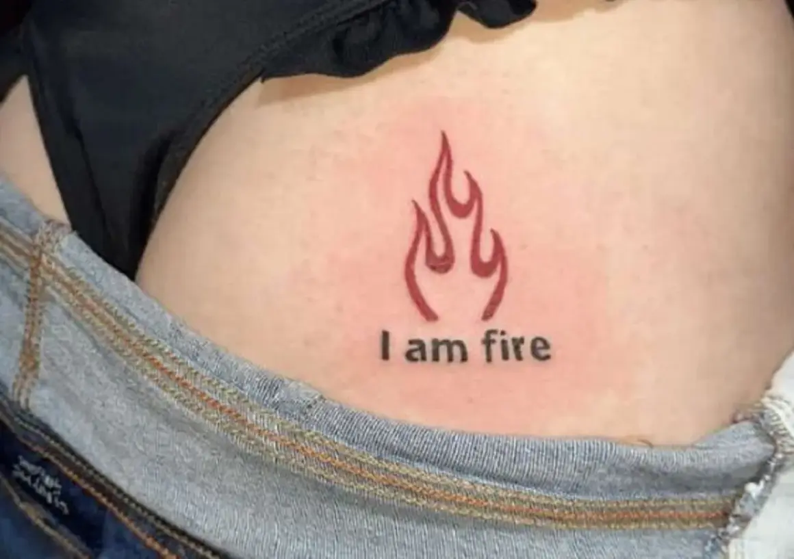 Płomień i napis "I am fire" na skórze, subtelny tatuaż na pośladku.