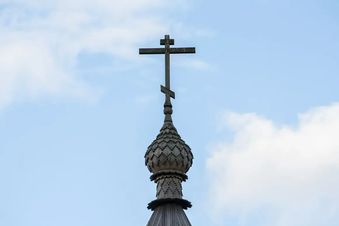 Drewniany krzyż na kopule cerkwi, symbol gruzińskiej religii prawosławnej, na tle błękitnego nieba z chmurami.