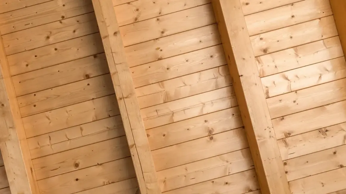 Holzdeckenpaneele mit sichtbaren Balken, bereit zum Streichen. Natürliche Holzmaserung.