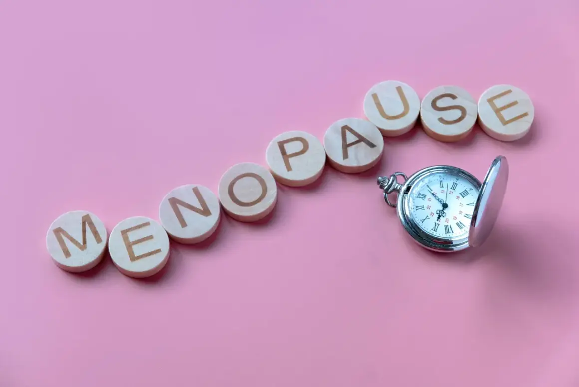 Drewniane kółka z literami układają napis "MENOPAUSE" obok kieszonkowego zegarka. Pytanie "ile trwa menopauza forum" nasuwa się samo.