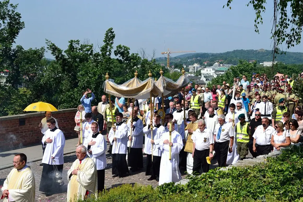 Procesja z monstrancją w słoneczny dzień, kiedy jest Boże Ciało. Ludzie w strojach liturgicznych i świeckich idą ulicą.