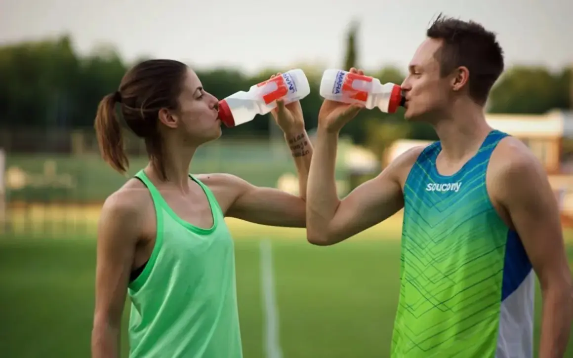 Zwei Athleten trinken nach dem Sport. Sie halten ihre Wasserflaschen und erfrischen sich auf dem Feld.
