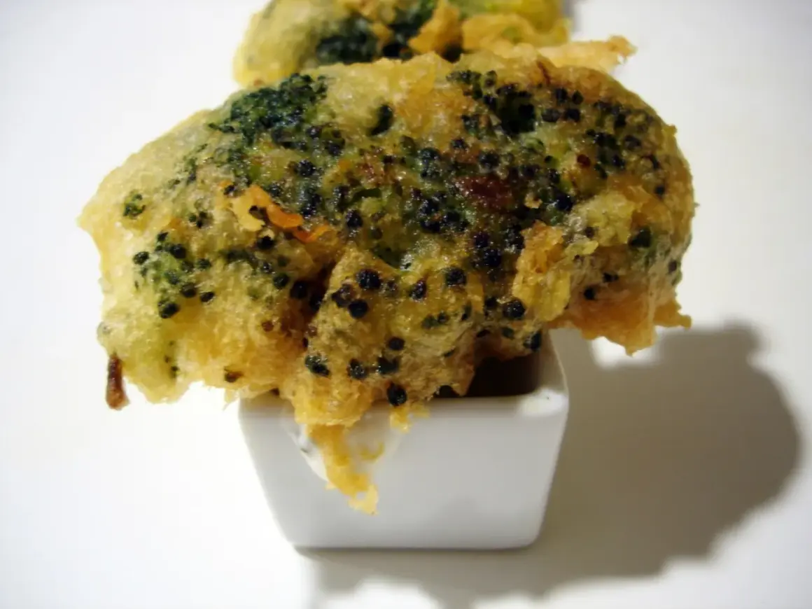 Brocoli en tempura crujiente, servido en un pequeño cuenco blanco con salsa.