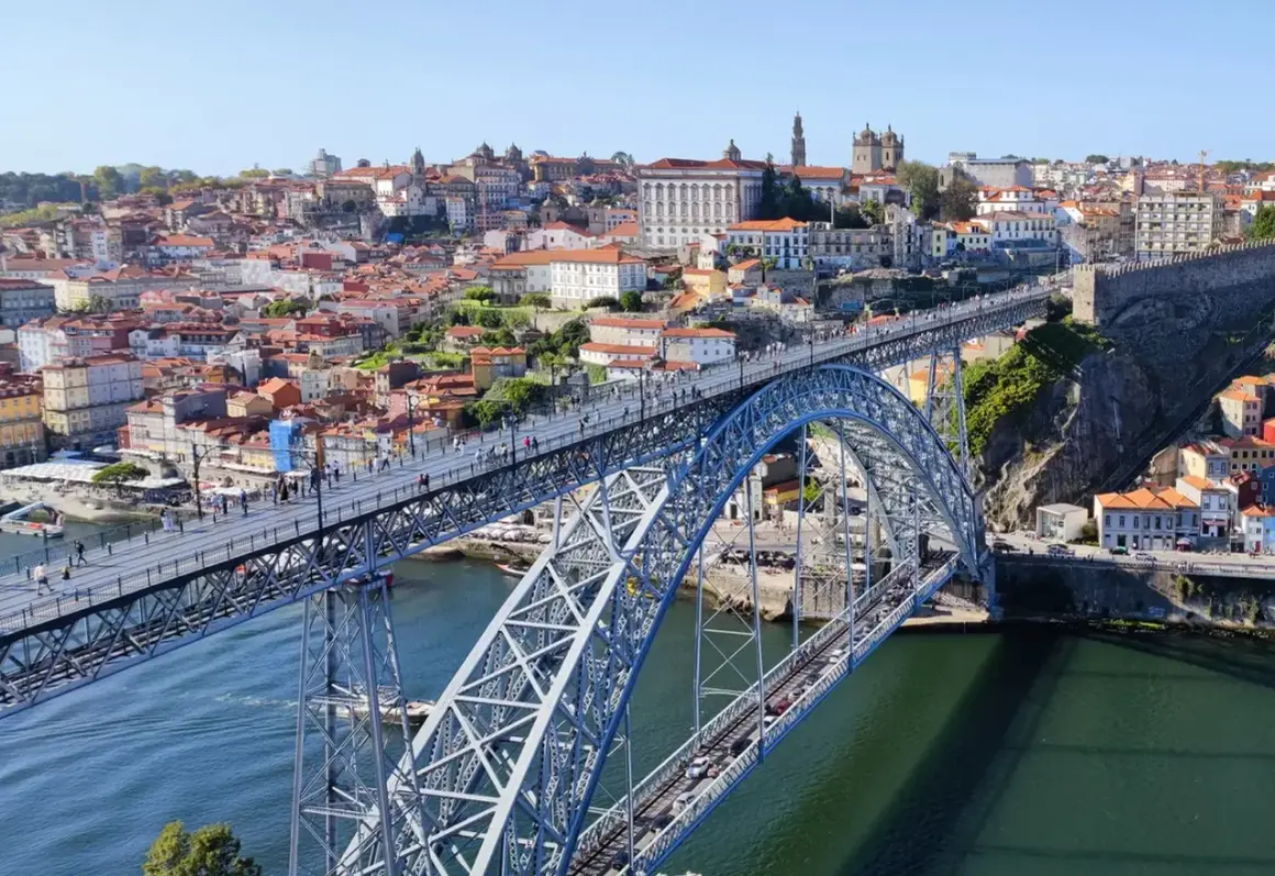 Most Ponte Dom Luís I w Porto, z widokiem na rzekę Douro i kolorowe budynki.