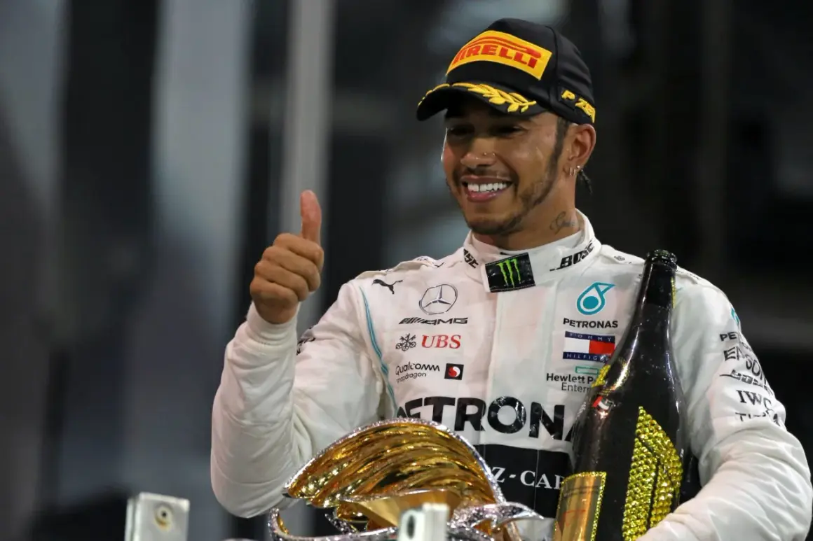 Lewis Hamilton, jeden z najlepsi kierowcy F1 wszechczasów, świętuje zwycięstwo z pucharem i szampanem.