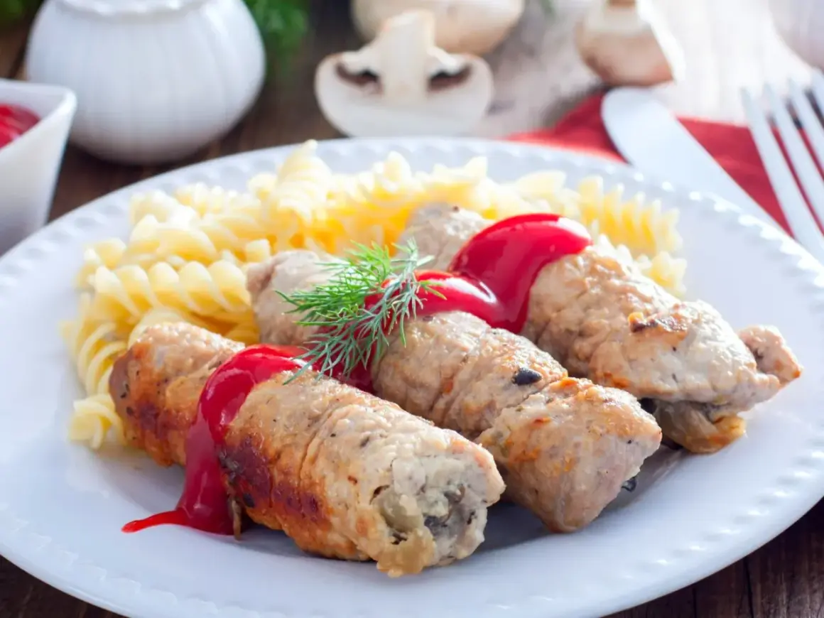 Roladki schabowe z pieczarkami, polane sosem, podane z makaronem fusilli i koperkiem.