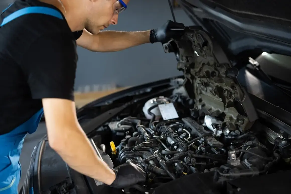 Mécanicien travaillant sur un moteur de voiture, vérifiant les composants pour éviter tout risque de colmatage.