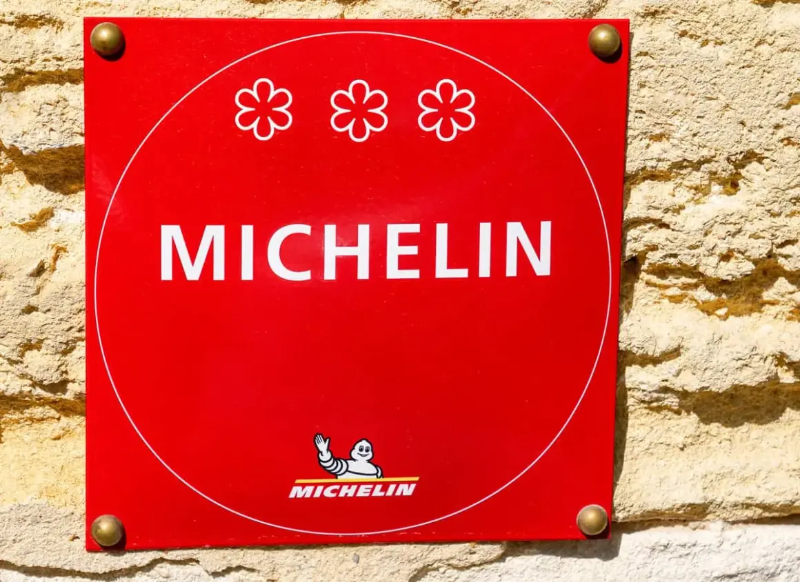 Targa rossa Michelin con tre fiori, simbolo di un ristorante 3 stelle Michelin.
