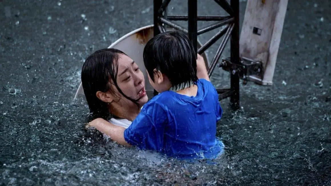 Dramatyczna scena z najlepszych filmów koreańskich: dziecko obejmuje tonącą kobietę w ulewnym deszczu.