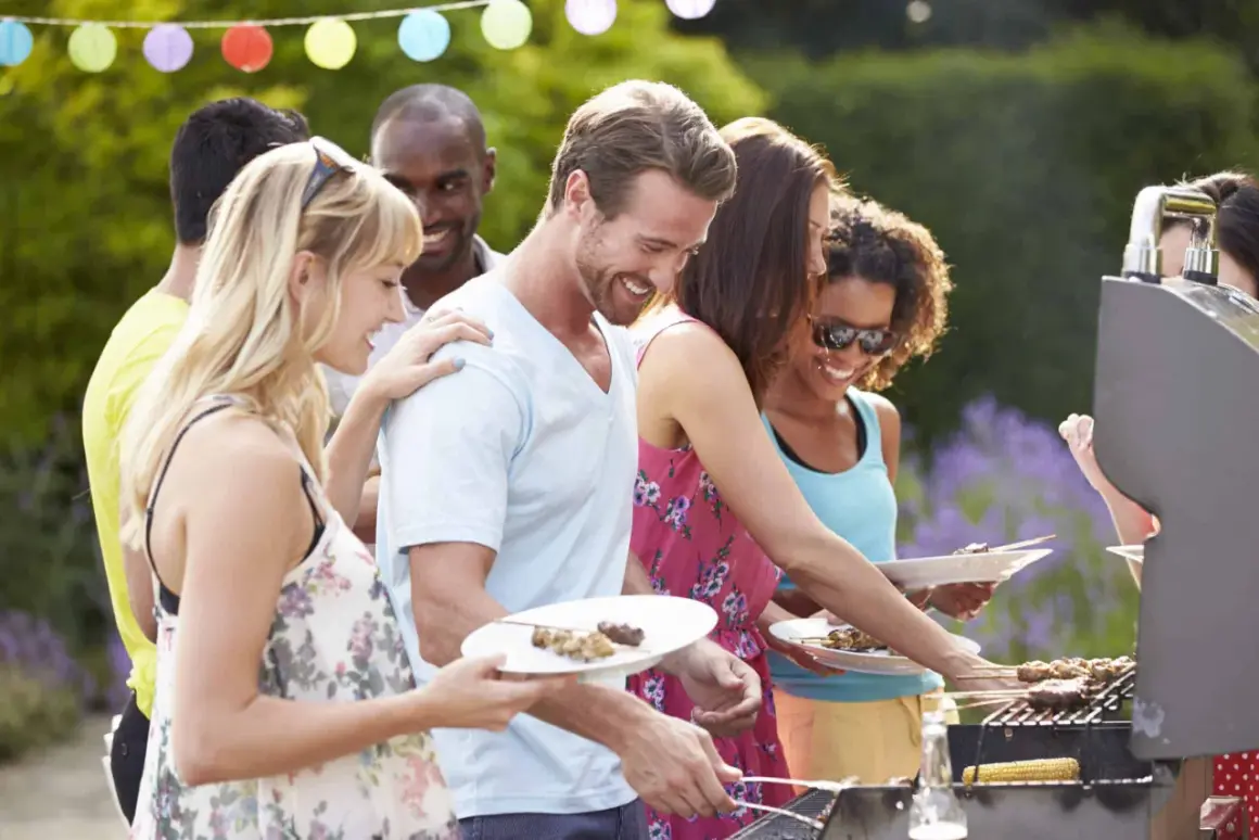 Des amis profitent d'un barbecue pour mariage en plein air, avec des brochettes et du maïs grillé.