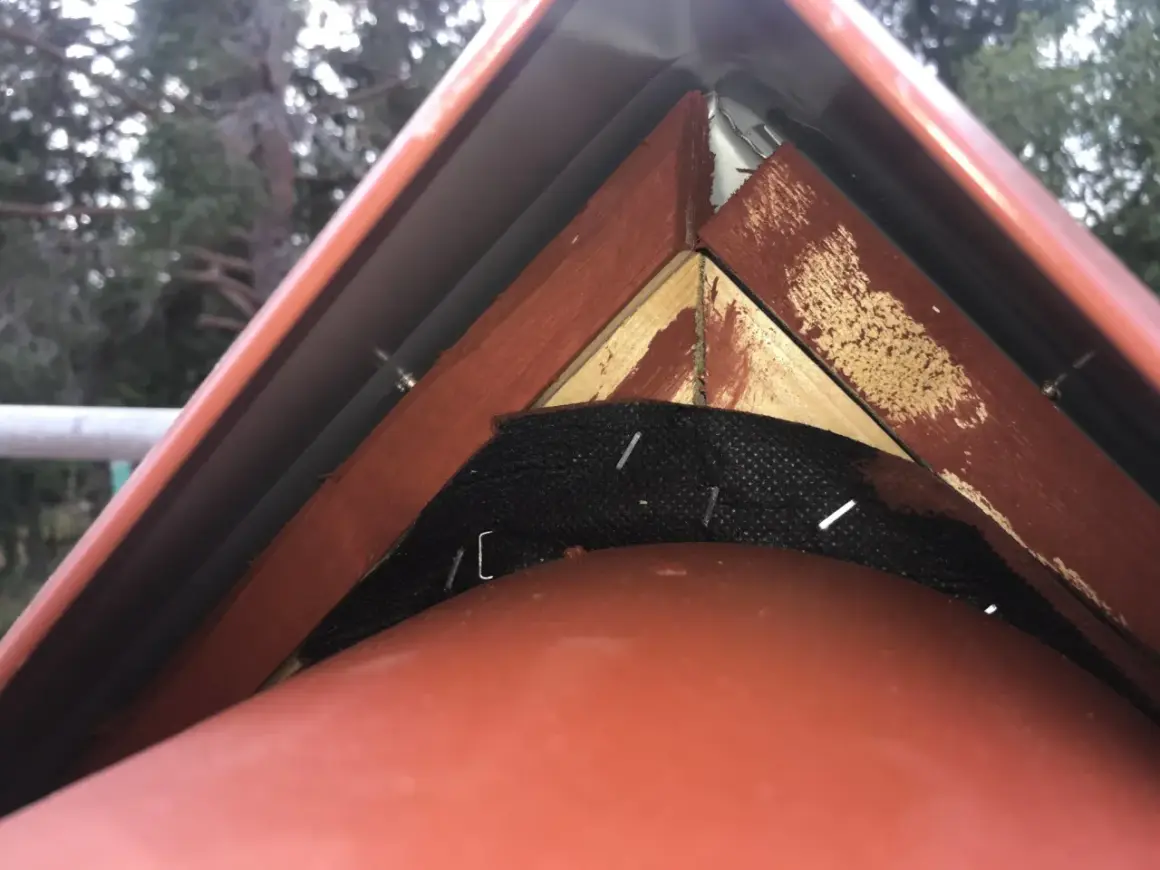 Detaljbild av taknock med vindskiveplåt och trädetaljer.