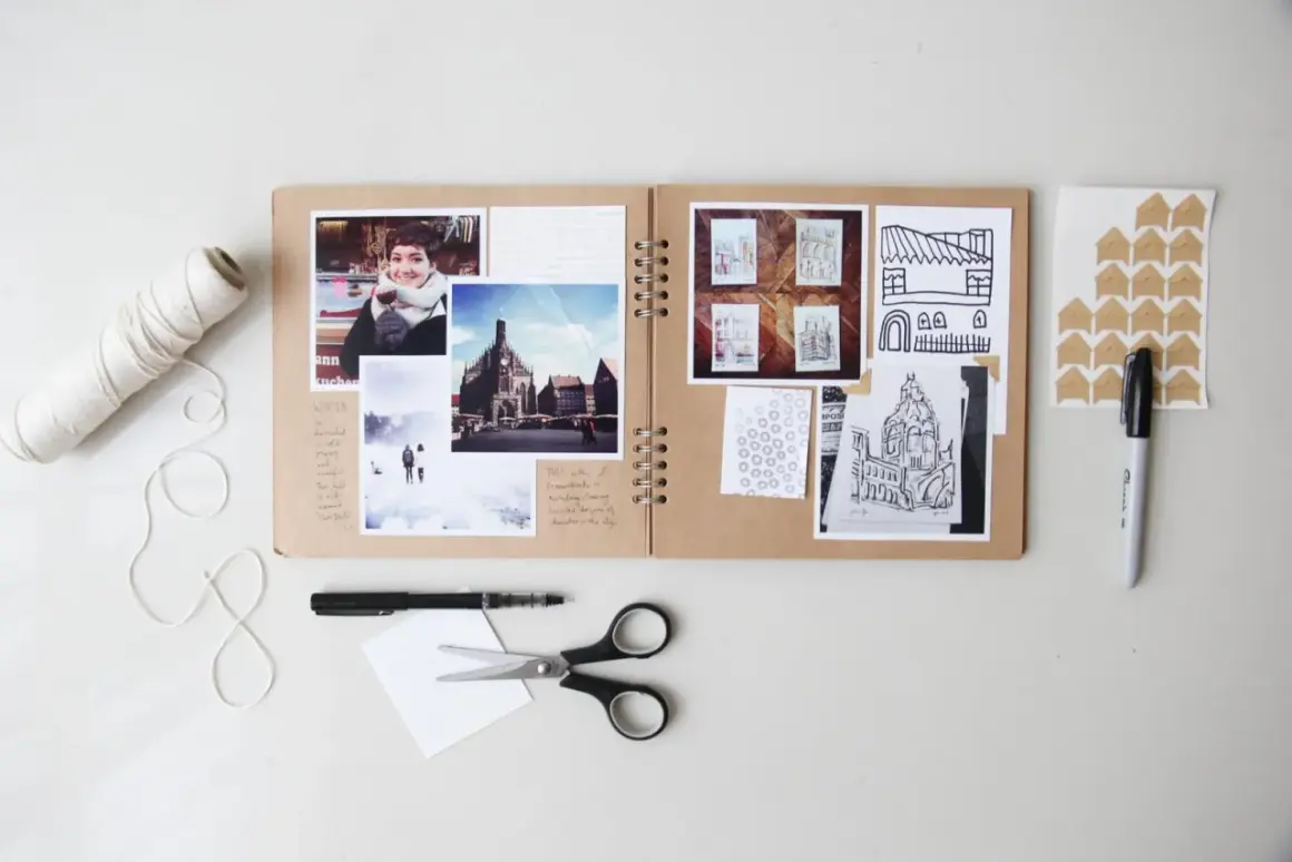 Oto przykład, co to jest scrapbooking: otwarta księga z przyklejonymi zdjęciami, rysunkami i notatkami, obok nożyczki, pisak i sznurek.
