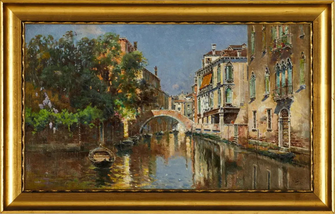 Un canal veneciano con un puente de arco, barcas y edificios históricos, pintado por Antonio Reyna Manescau.