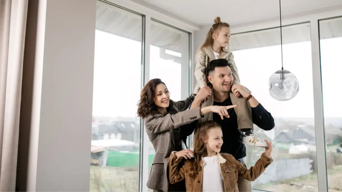Famiglia felice in una casa luminosa, con la madre che indica il futuro. Nonostante si possa vendere casa senza lasciare a mio figlio nulla, l'amore è il vero patrimonio.