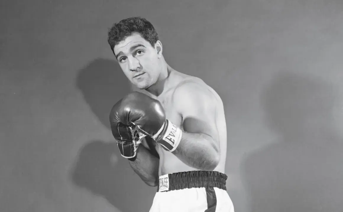 Boxer Rocky Marciano poses with his powerful Rocky Marciano hands in boxing gloves, ready for action.