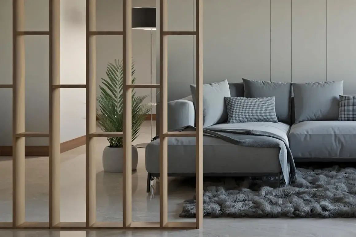 Ein modernes Wohnzimmer mit einer stilvollen Trennwand, die man auch selber bauen könnte. Ein bequemes Sofa und eine Pflanze schaffen Gemütlichkeit.