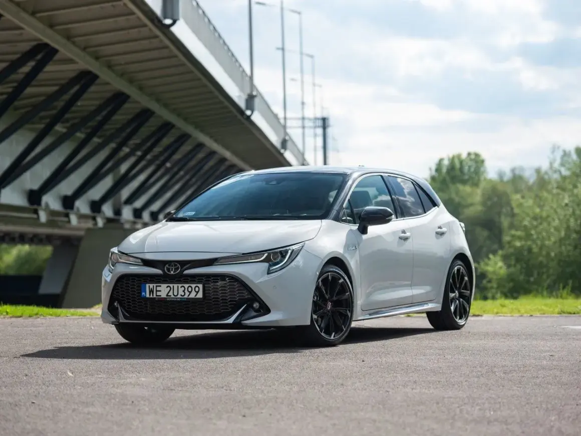 Biała Toyota Corolla GR Sport z czarnymi felgami stoi pod mostem.