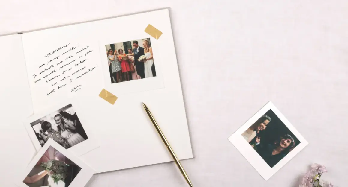 Vœux de mariage manuscrits sur un album, avec des photos instantanées de la cérémonie et du couple. Un stylo doré repose à côté.