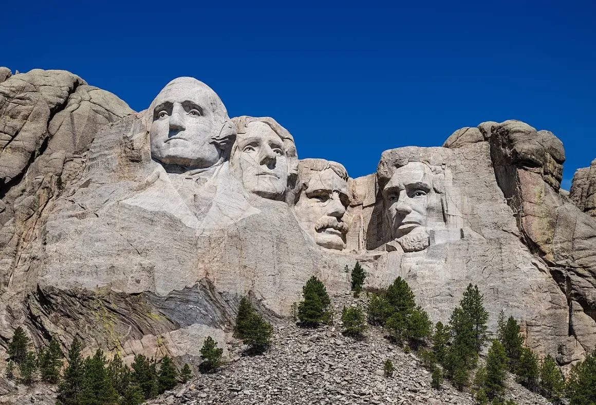 Las caras de cuatro presidentes de EE.UU. talladas en el **Monte Rushmore**, bajo un cielo azul intenso.