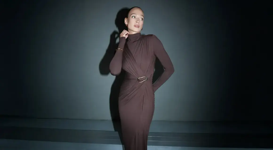 Elegancka, brązowa sukienka maxi z golfem i drapowaniem podkreśla sylwetkę. Długość sukienki do wzrostu modelki jest idealna.