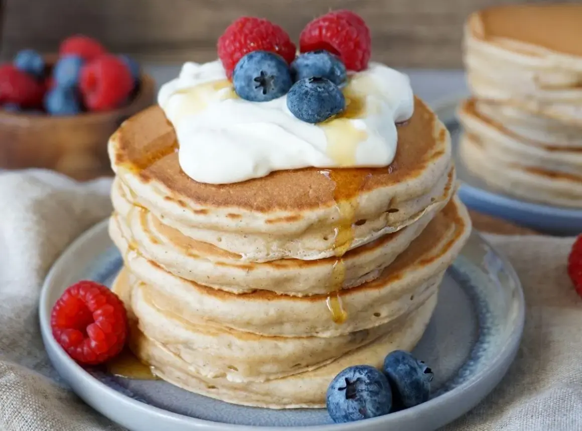 Fluffige Bananenpfannkuchen mit Sahne, Beeren und Honig. Ein köstlicher Frühstückstraum!