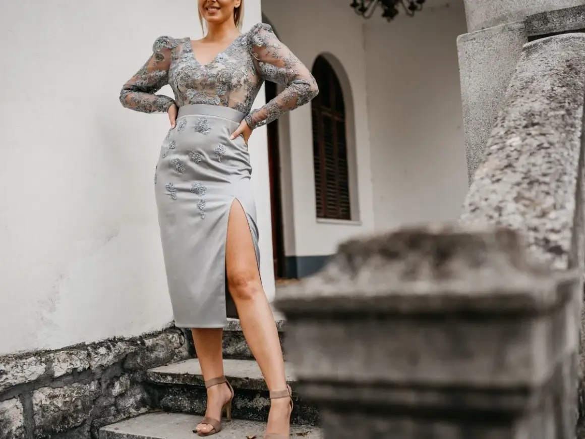 Elegancka szara sukienka z rozcięciem i koronkową górą. Idealne buty do szarej sukienki to te na obcasie, w cielistym kolorze.