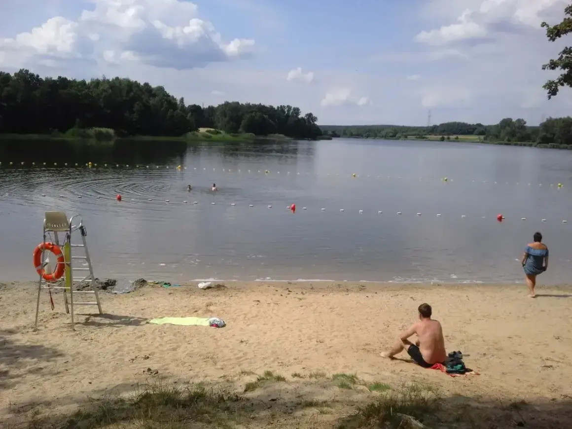 Słoneczny dzień nad zalewem Rybnik. Kąpielisko z ratownikiem, plażą i ludźmi kąpiącymi się w wodzie.