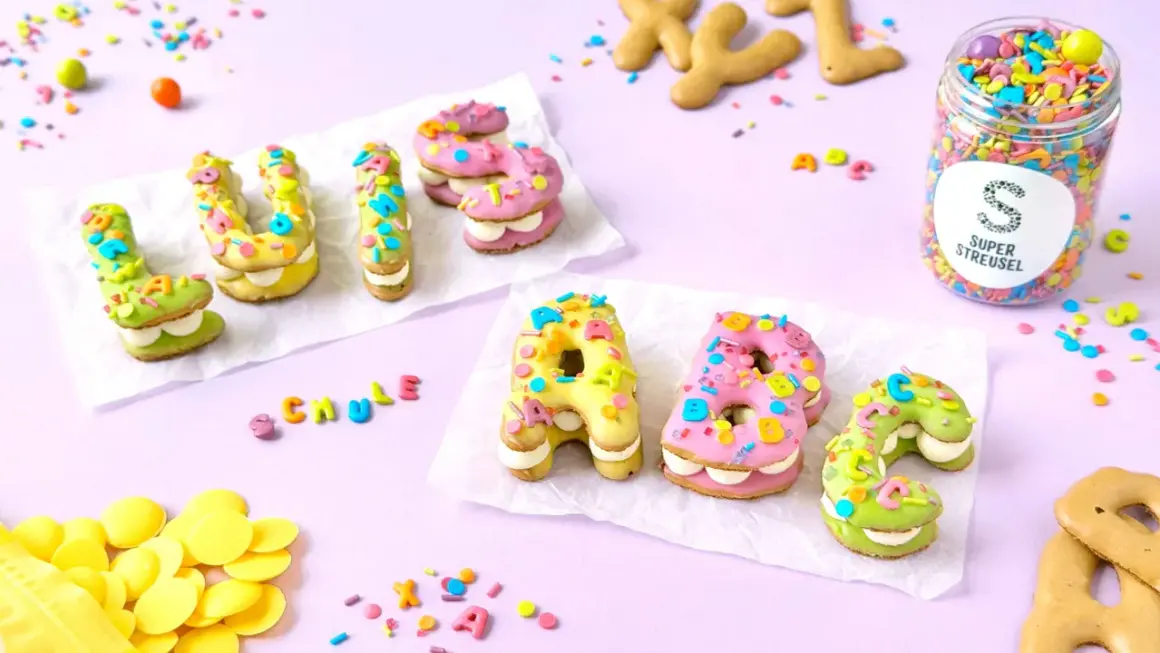 Bunte Buchstabenkekse, inspiriert von einem russisch brot rezept, mit Zuckerguss und Streuseln verziert.