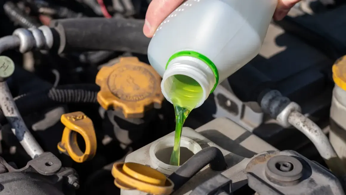 Main verte versée dans le réservoir, assurant le bon niveau liquide de refroidissement du moteur.