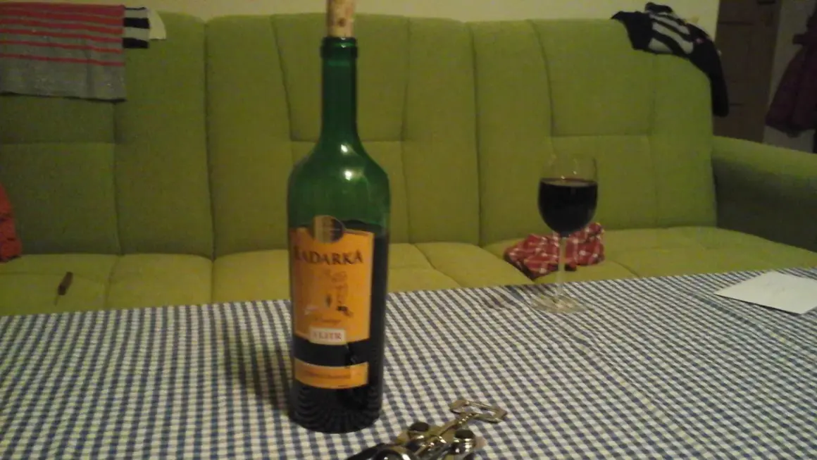 Butelka Kadarka na stole, obok kieliszek z winem. Zastanawiam się, kadarka ile procent ma w sobie?