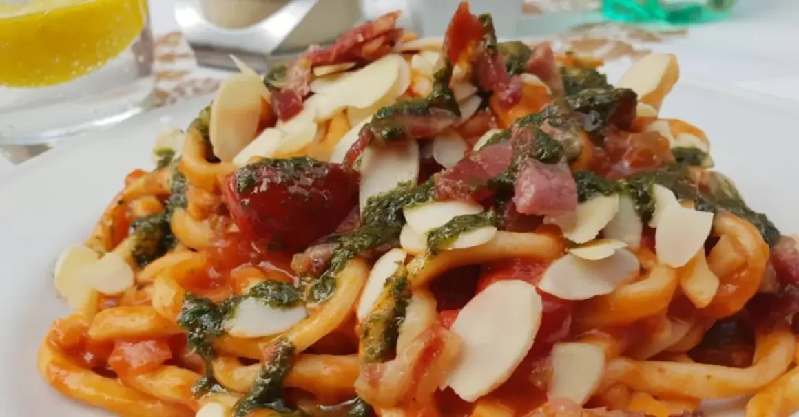 Pasta con pomodoro, pesto, mandorle e pancetta croccante, un piatto da gustare all'enoteca Civita.