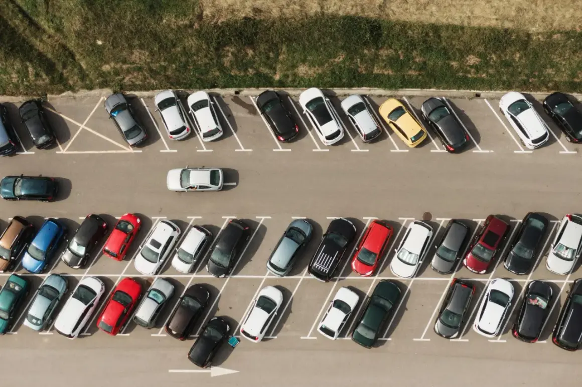Widok z góry na parking z samochodami. Widać jak prawidłowo wykonać parkowanie skośne kiedy skręcać.