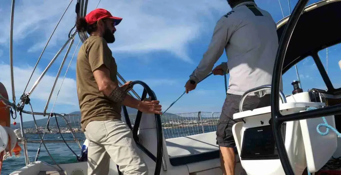 Due uomini in barca a vela, uno al timone, l'altro che regola le cime. Il **significato** di strambare è cambiare rotta.