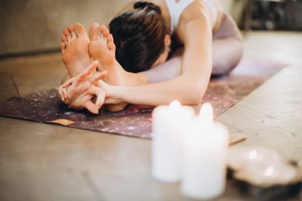 Una mujer en postura de yoga, con las manos entrelazadas en los pies. La práctica de **sadhana** es un camino de autoconocimiento.