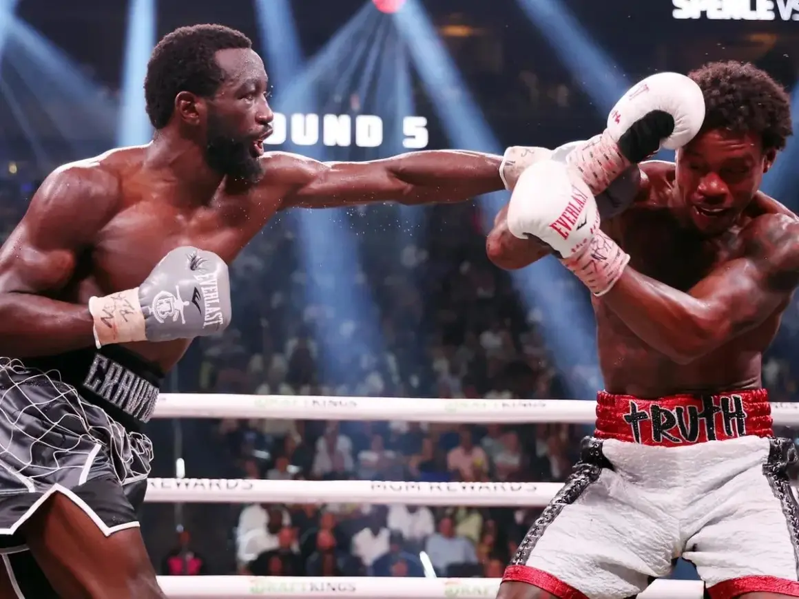 Terence Crawford lands a punch wearing grey Everlast gloves. His opponent, wearing white Everlast gloves, attempts to block.