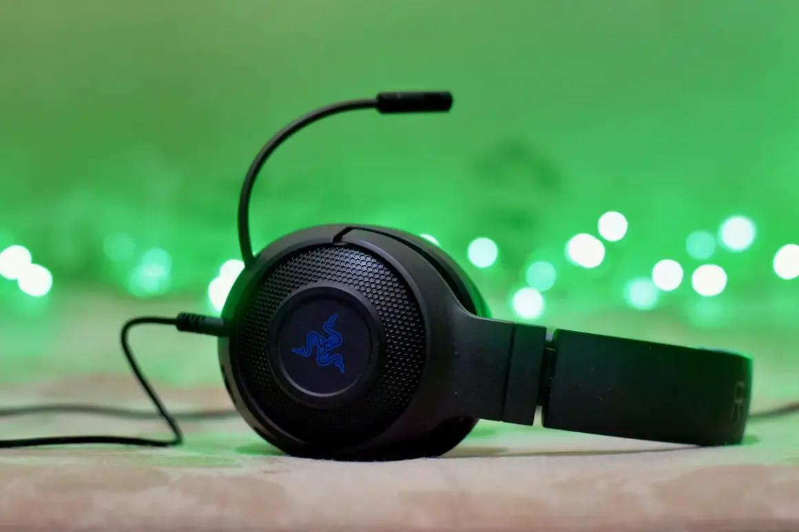 Słuchawki gamingowe Razer z mikrofonem, podłączone przez combo jack, na tle zielonych światełek.