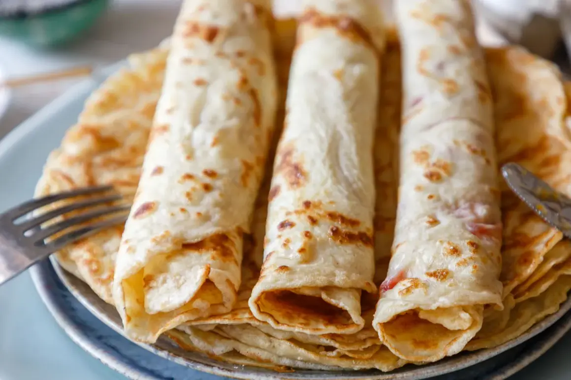 Drei goldbraune Pfannkuchen, aufgerollt und gestapelt, ein sehr gutes Pfannkuchen Rezept, bereit zum Genießen. Eine Gabel liegt daneben.