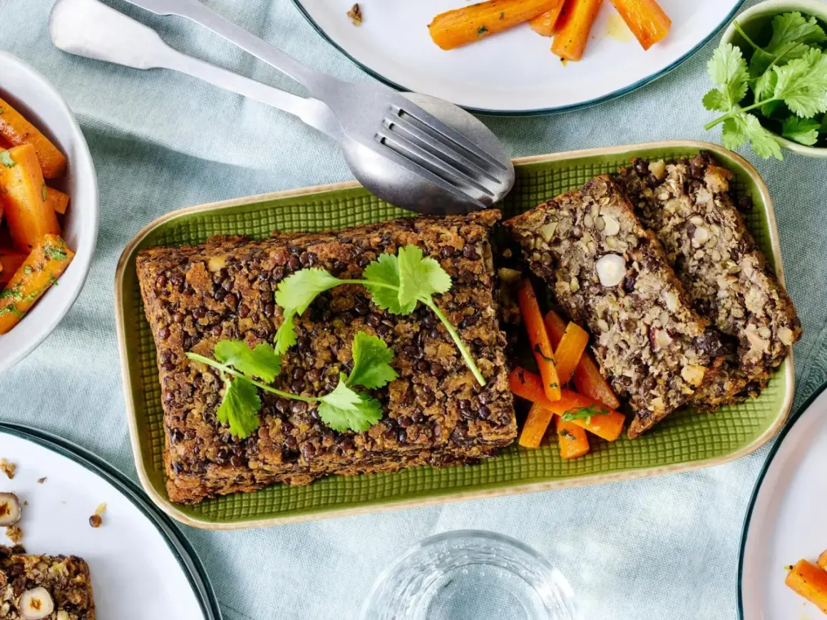 Herzhaftes Linsen-Nuss-Brot mit glasierten Karotten – ein köstliches vegetarisches Weihnachtsessen, garniert mit frischer Petersilie.