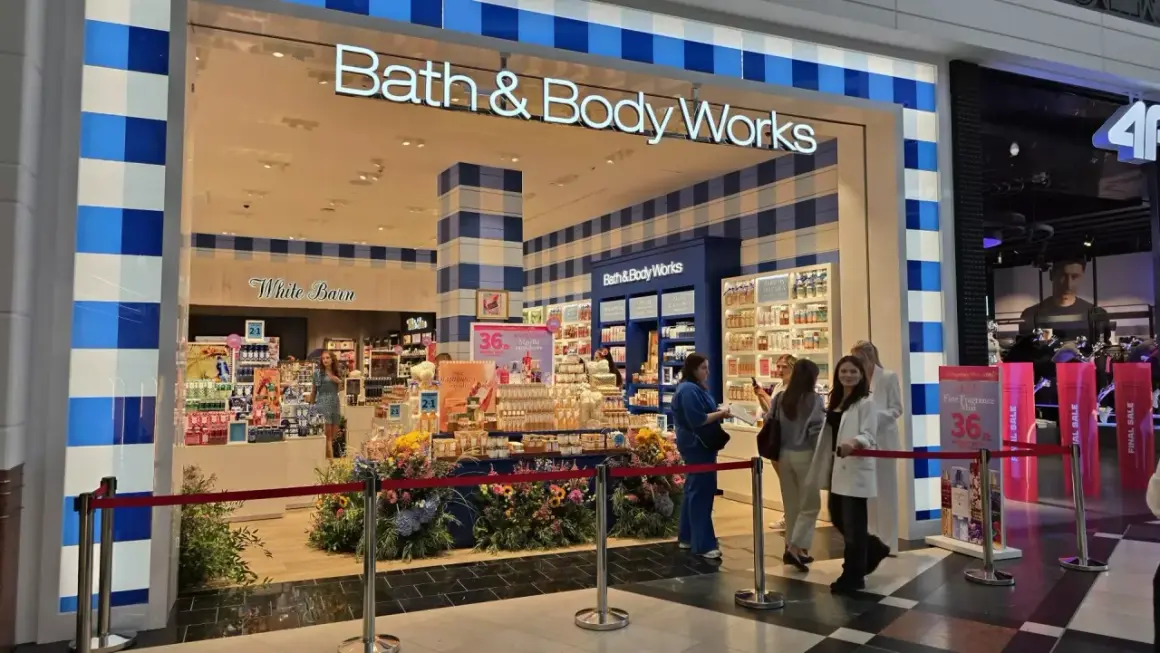 Sklep Bath & Body Works z promocjami, wystawą kwiatów i klientami.