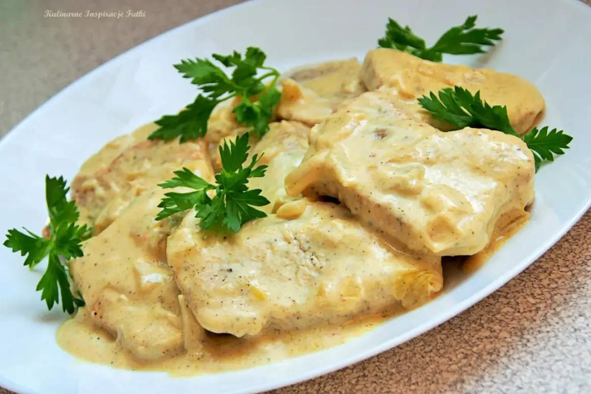 Pyszny filet z indyka w sosie śmietanowym, udekorowany natką pietruszki. Danie wygląda apetycznie i zachęca do spróbowania.