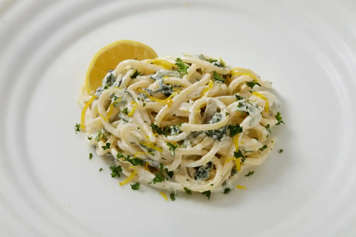 Pâtes crémeuses au citron et persil, garnies d'une tranche de citron.