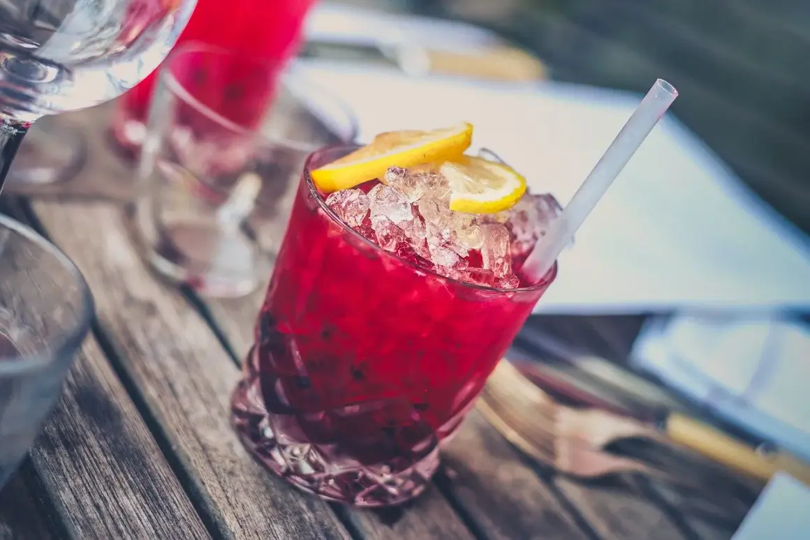 Czerwony drink z lodem i cytryną, prawdopodobnie z dodatkiem grenadyny. Co to jest grenadyna? Syrop z granatów, nadaje napojom piękny kolor i słodycz.
