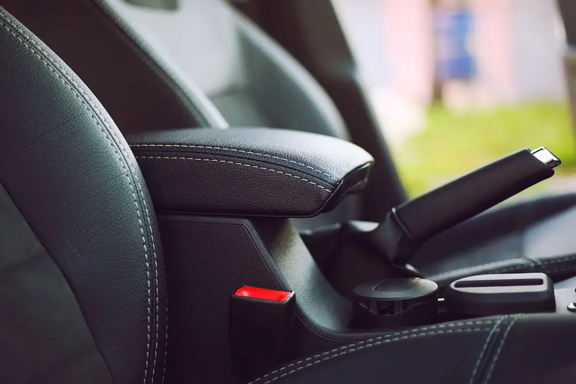 Skórzany podłokietnik i dźwignia hamulca ręcznego w samochodzie. Funkcja auto hold zapewnia komfort podczas postoju.