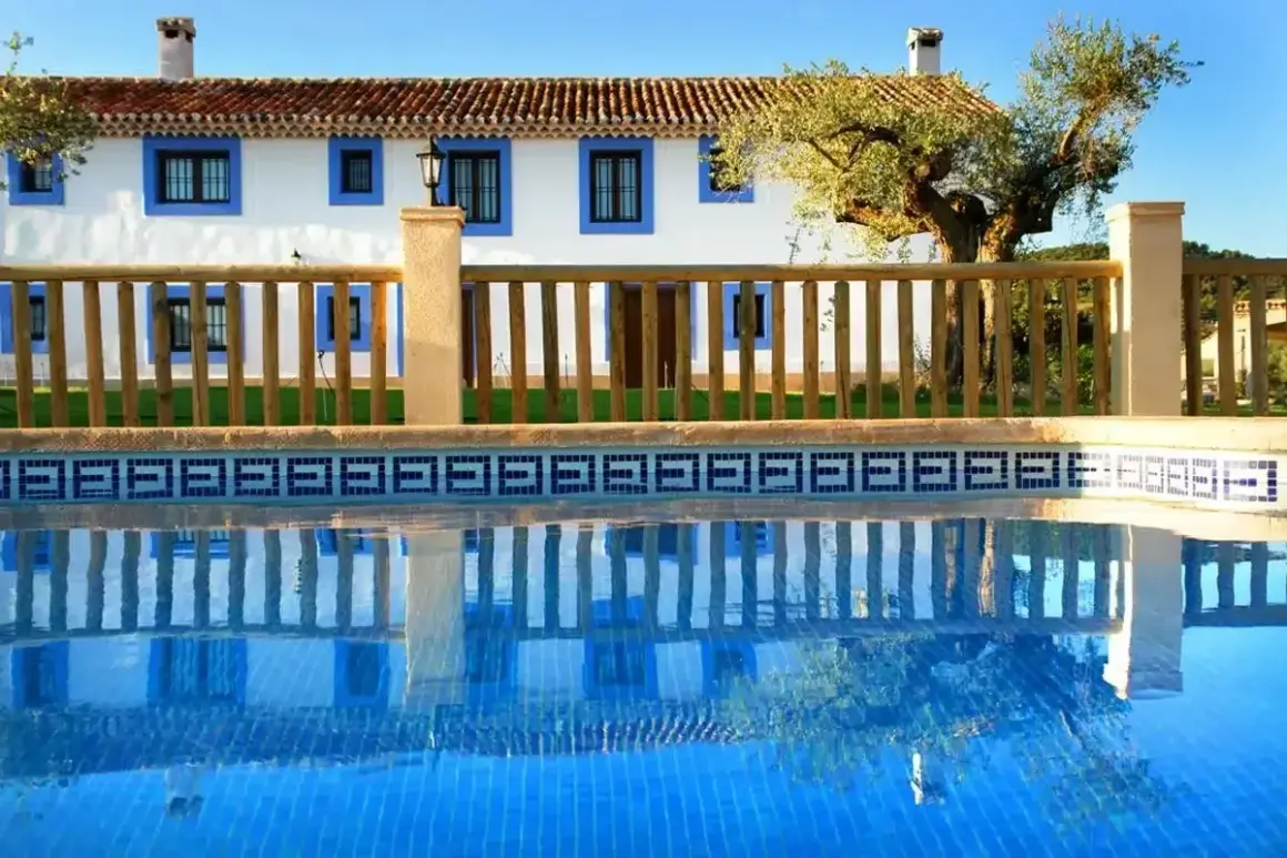 El cortijo Los Pradillos, con su piscina azul y reflejos, invita a un descanso bajo el sol andaluz.