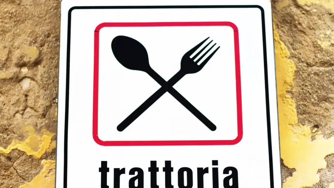 Segnale con forchetta e cucchiaio incrociati, che indica una trattoria. Un invito a gustare sapori autentici, diverso dall'osteria.